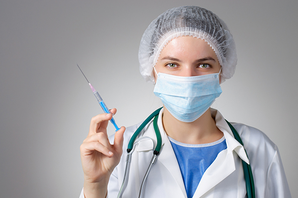 врач в медицинской маске со шприцом в руке